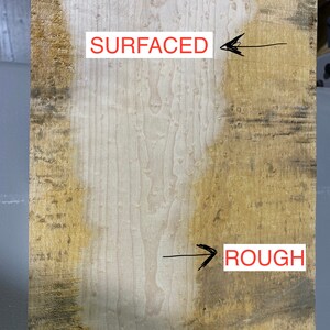 May include: Close-up of a wood panel showing the difference between a rough and a surfaced finish. The left side of the panel is smooth and light brown, while the right side is rough and dark brown. The words "SURFACED" and "ROUGH" are written on the panel.