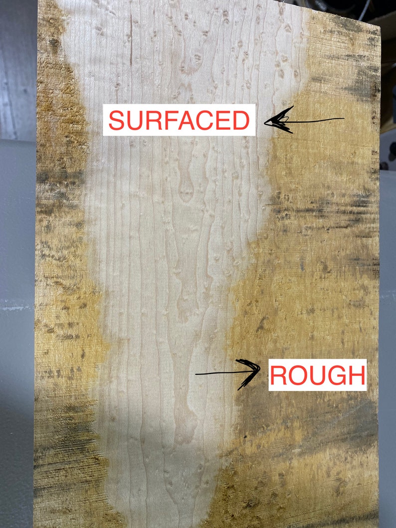 May include: Close-up of a wood panel showing the difference between a rough and a surfaced finish. The left side of the panel is smooth and light brown, while the right side is rough and dark brown. The words "SURFACED" and "ROUGH" are written on the panel.