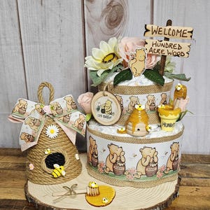 May include: A Winnie the Pooh themed diaper cake with a honey pot, a beehive, and a sign that says "Welcome to the Hundred Acre Wood".