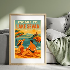 May include: A framed poster featuring the words "ESCAPE TO LAKE SEVAN." The image shows a couple on a beach, with parasols, a lake, mountains, and a castle. The artwork uses orange, blue, and yellow. The poster is in a wooden frame.