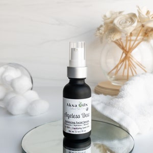 Może przedstawiać: Czarna szklana butelka z srebrną pompką i białą etykietą z napisem "Aksa Oils Natural Skin Care Ageless Dew Balancing Facial Serum Restores Hydrates Renews Co Q10 + Clarifying Seed Oils Net Wt. 1.2 oz | 35 ml".