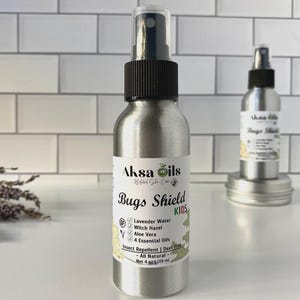 May include: Aksa Oils Bugs Shield KIDS insect repellent spray in a silver metal bottle. The label lists ingredients like lavender water, witch hazel, and aloe vera. The bottle is 4 fl oz / 119 ml.