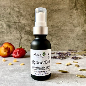 Może przedstawiać: Czarna szklana butelka z srebrną pompką i białą etykietą z napisem "Aksa Oils Natural Skin Care Ageless Dew Balancing Facial Serum Restores Hydrates Renews Co Q10 Clarifying Seed Oils Net Wt. 1.2 oz | 35 ml"