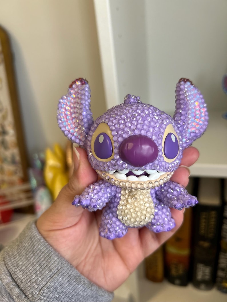 May include: Purple and white rhinestone Stitch figurine with a toothy grin.