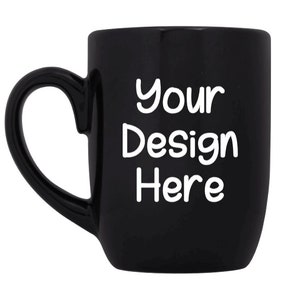 May include: A black ceramic mug with a white handle. The mug has the text "Your Design Here" printed on the front in a white, handwritten font.