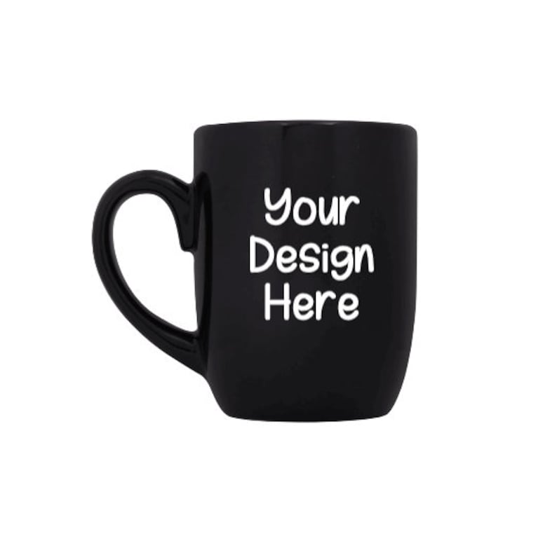 May include: A black ceramic mug with a heart-shaped handle. The mug has the text "Your Design Here" printed on the front in white.
