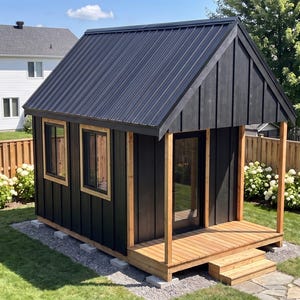 May include: A small detached shed with black vertical siding, a dark metal roof, and a natural wood porch. The structure features two windows with wood trim, a glass door, and a set of wooden steps leading up to the front entrance.