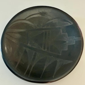May include: A white ceramic mug with a black handle and the text "But First, Coffee" in a bold, black font. The mug is sitting on a wooden surface. The mug is approximately 4 inches tall.