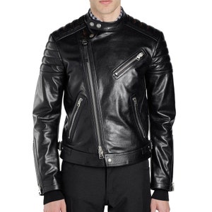 May include: A black leather motorcycle jacket with a zipper closure and multiple pockets. The jacket has a stand-up collar and a quilted design on the shoulders and sleeves.