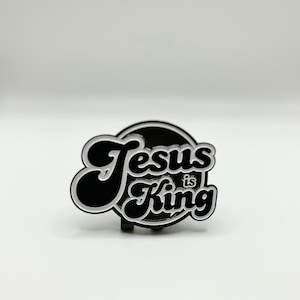 May include: Black and white enamel pin with the text "Jesus is King" in a retro font.