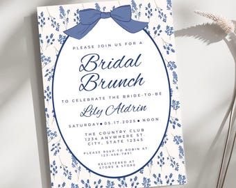 Puede incluir: Una invitación blanca con un patrón floral azul y un lazo azul. La invitación es para un brunch nupcial para celebrar a Lily Aldrin el sábado 17 de mayo de 2025 al mediodía. El evento se llevará a cabo en The Country Club, 1234 Anywhere St., City, State 12345. Por favor, confirma tu asistencia con Robin al 123-456-7891. La invitación también incluye información sobre dónde está registrado la pareja.