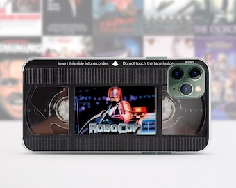 May include: A black and clear phone case with a retro VHS tape design. The case features a scene from the movie Robocop with the text "Robocop" printed on the case. The case has a cutout for the phone's camera.