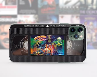 May include: A black and clear phone case with a VHS tape design. The case features a graphic of the movie "Big Trouble in Little China" with the text "Insert this side into recorder" and "Do not touch the tape inside".