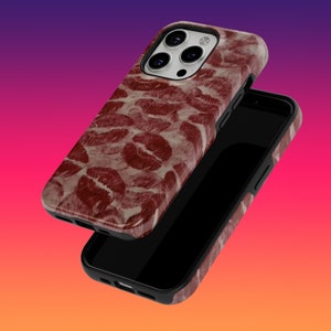 May include: A black phone case with a red and white pattern of lips. The case is designed for an iPhone with a camera bump.
