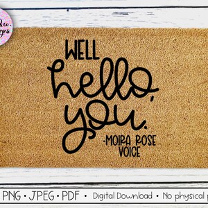May include: A brown doormat with the text "WELL hello you" in black cursive font. Below the text is "MOIRA ROSE VOICE" in smaller black font.