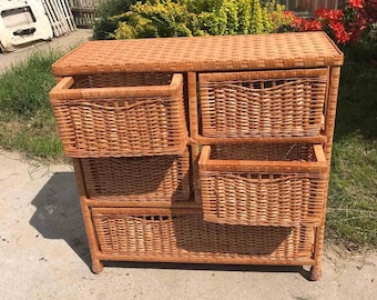 May include: A wicker storage cabinet with five drawers. The cabinet is made of natural woven wicker and has a light brown color.