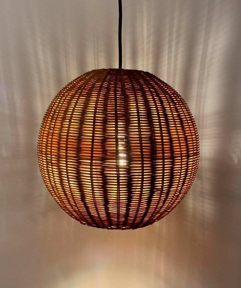 May include: A round, woven wicker pendant light fixture with a warm, glowing light emanating from inside.