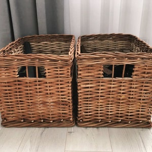 Puede incluir: Dos cestas de almacenamiento de mimbre marrón con un patrón tejido. Las cestas tienen una forma rectangular y están hechas de materiales naturales.