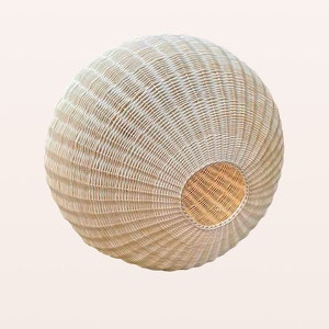 May include: A white wicker pendant light fixture with a round shape and a woven pattern. The light fixture has a natural wood color on the inside.