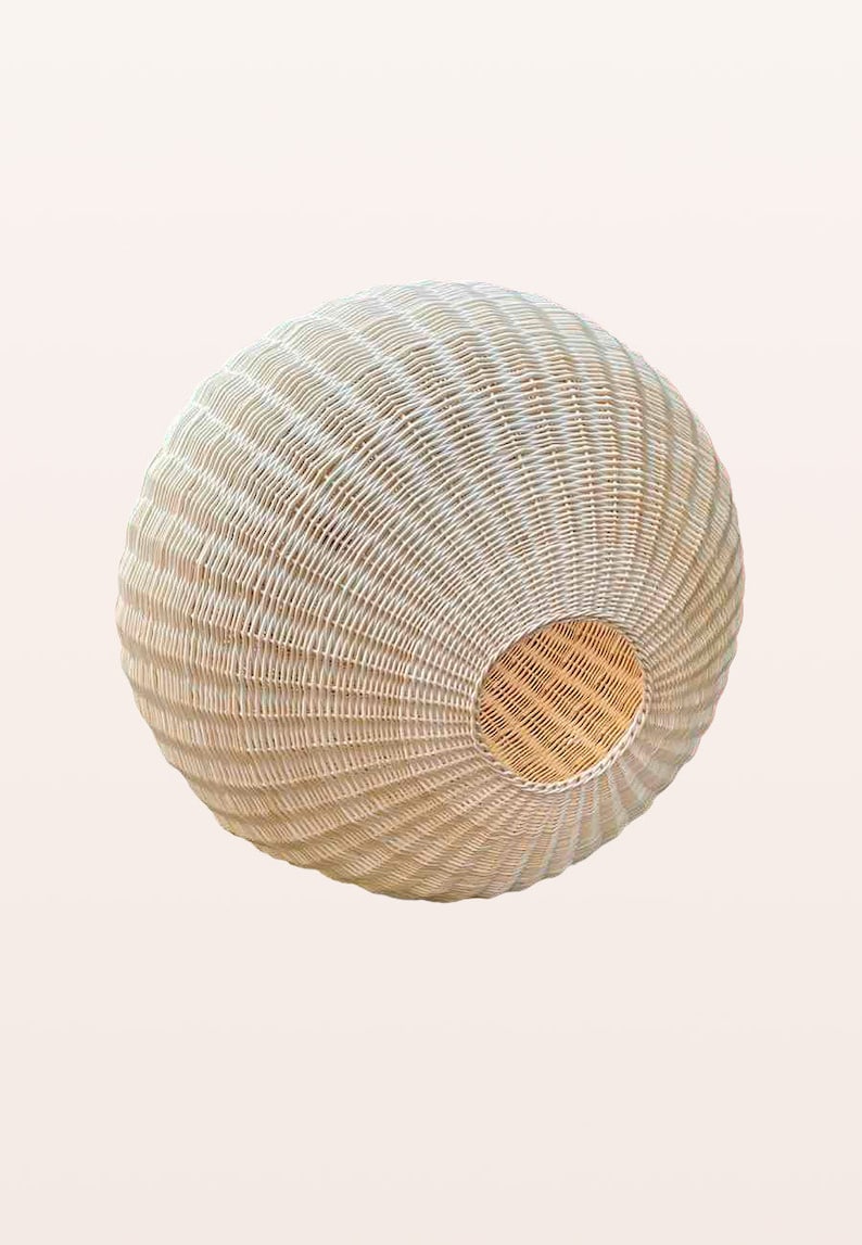 May include: A white wicker pendant light fixture with a round shape and a woven pattern. The light fixture has a natural wood color on the inside.