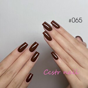 Puede incluir: Primer plano de manos con uñas marrones en forma de ataúd. Las uñas están pintadas de un color marrón intenso. La imagen incluye el texto "#065" y "Ccstr nail".