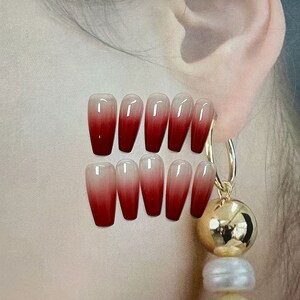 Op de afbeelding: Set van tien rode en witte ombre nepnagels. De nagels zijn lang en in een kistvorm.