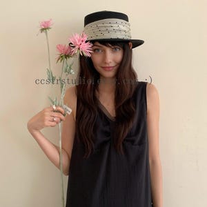 Puede incluir: Un sombrero negro con una banda de cinta beige ancha y fruncida con pequeños puntos negros. El sombrero tiene una corona estructurada y un ala plana. El texto ccstrstudio.etsy.com :) es visible en el centro de la imagen.