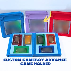 May include: A blue, purple, and red plastic game cartridge holder with a yellow arrow pointing to the purple case. The open blue holder contains six smaller game cartridges in red, orange, green, and black, with the text CUSTOM GAMEBOY ADVANCE GAME HOLDER.
