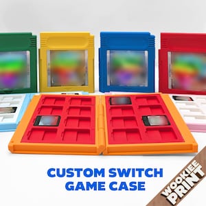 Puede incluir: Una colección de estuches de plástico para cartuchos de juego en verde, amarillo, azul y rojo, junto a un estuche naranja abierto con ranuras interiores rojas para tarjetas de juego. El texto "CUSTOM SWITCH GAME CASE" y "WOOKIEE PRINT" es visible.