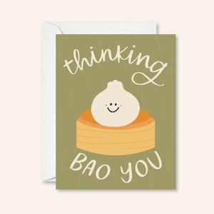 Puede incluir: Una tarjeta verde con el texto "thinking bao you" y una ilustración de dibujos animados de un pan al vapor con una cara sonriente.