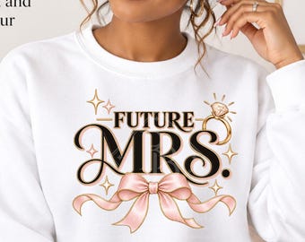 May include: A white crewneck sweatshirt featuring a graphic print that says FUTURE MRS. in black lettering, accompanied by a gold diamond ring illustration and a light pink ribbon bow. The design includes small gold star accents on the front.