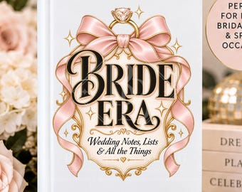 May include: A white hardcover journal featuring the text BRIDE ERA and Wedding Notes, Lists & All the Things. The cover design includes a gold diamond ring illustration, a large pink ribbon, and decorative gold flourishes on a white background.