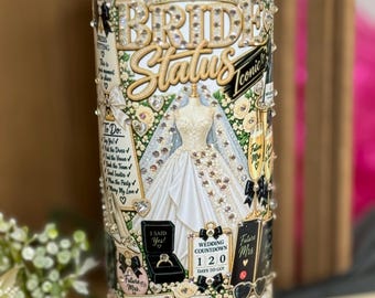 May include: A white cylindrical tumbler featuring a collage of wedding-themed graphics including a bridal gown, a tiara, a ring box, champagne flutes, and a wedding countdown calendar. The text reads Bride Status, Iconic, To Do, I Said Yes, and Bride Vibes.