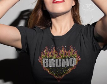 以下が含まれることがあります： 「BRUNO」の文字が入った、炎の形をしたラインストーンのデザインが施された黒いTシャツ。炎は黄色、オレンジ、赤色で表現されています。Tシャツは半袖です。