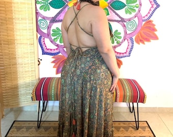 May include: A long, flowing maxi dress with a floral print in shades of green, brown, and orange. The dress has a criss-cross back and a tassel detail at the bottom.