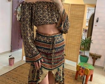 Könnte beinhalten: Ein zweiteiliges Outfit mit einem kurzen, schulterfreien Oberteil und einem langen, asymmetrischen Rock. Beide Teile haben einen farbenfrohen, geometrischen Druck mit floralen Akzenten.