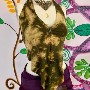 May include: A green and brown tie-dye halter top with a beaded detail down the front. The top is made of a soft, flowing fabric and has a relaxed fit.