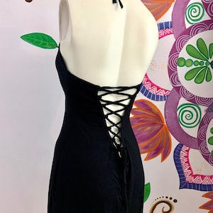 Puede incluir: Vestido negro de tirantes con detalle de encaje en la espalda. El vestido está hecho de una tela suave y elástica y tiene una silueta ajustada.