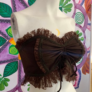 May include: A brown strapless top with a lace trim and a tie at the front.
