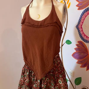 Op de afbeelding: Een bruin haltertop met een gefranst decolleté en een bruin met groene bloemenprint rok.