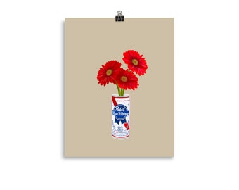 May include: Three red gerbera daisies in a can of Pabst Blue Ribbon beer.
