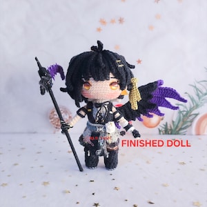 May include: A handmade crochet doll with black hair, wearing a black and white outfit, and holding a staff with purple accents. The doll has yellow eyes and a pair of black and purple wings. The text "FINISHED DOLL" is visible.