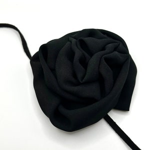 May include: A black fabric rose with a long black ribbon attached.