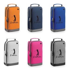 Puede incluir: Seis bolsas de zapatos de golf personalizadas en diferentes colores: naranja, azul marino, azul real, gris, rosa y negro. Cada bolsa presenta una silueta de golfista y el nombre "John" impreso en la parte delantera.