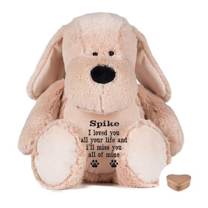 May include: A plush beige dog with floppy ears and a black nose. The dog has the name "Spike" and a message embroidered on its chest. Two paw prints are below the message. A small, heart-shaped, gold-colored box is to the right.