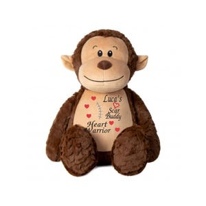 May include: A brown plush monkey with a tan face and ears. The monkey features the text "Luca's Scar Buddy Heart Warrior" with red hearts and a stitched line design on its chest. It is a soft toy.