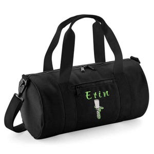 Op de afbeelding: Zwarte sporttas met een hoofdvak met ritssluiting, een voorvak met ritssluiting en een afneembare schouderriem. De tas heeft twee zwarte handvatten en de naam "Erin" in groen geborduurd met een groene afbeelding.