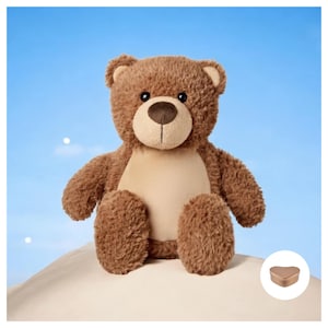 May include: A brown teddy bear sitting on a white surface with a small gold heart-shaped box in the bottom right corner.