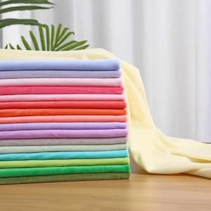 May include: A stack of folded fabric squares in a variety of colors including light yellow, lavender, pink, red, orange, peach, purple, gray, light blue, turquoise, lime green, bright green, and olive green, with a long piece of yellow fabric.