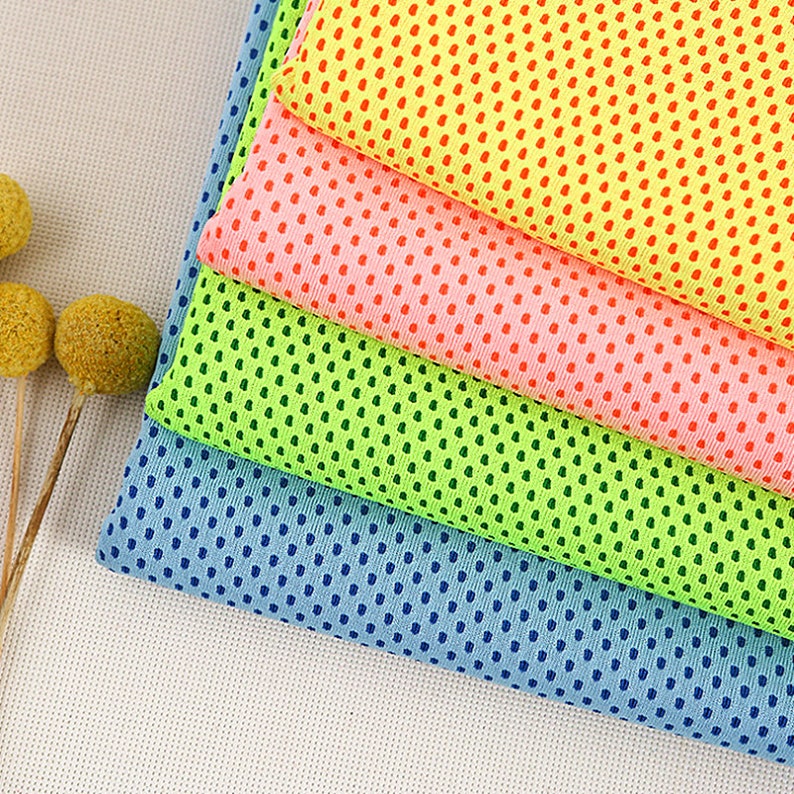 May include: A stack of cooling towels in various colors: yellow, pink, green, and blue. Each towel has a dotted pattern. The towels are made of a lightweight, breathable fabric, perfect for staying cool during workouts or outdoor activities.